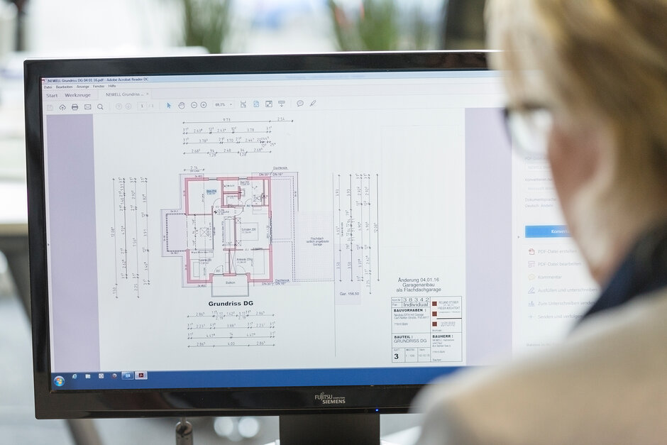 Planung bei axotherm – eine Fra sitz an einem Computer, auf dem Bildschirm wird geplant, wo genau im Raum die Infrarotkabine installiert werden kann.